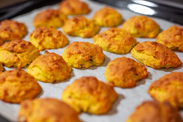 Bright orange Pumpkin cookies baked in the oven on an iron baking sheet on baking paper