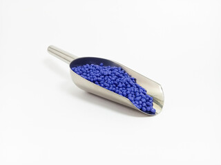 blue masterbatch plastic granules, polymer carries colorful pigments with small scoops poured into white background, suitable for industrial plastic company profile product catalog design
