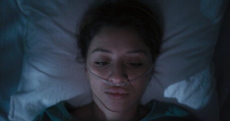 Tired female patient in hospital ward surfs Internet in the middle of the night.