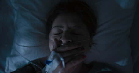 Tired female patient in hospital ward surfs Internet in the middle of the night.