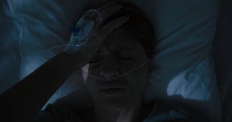 Tired female patient in hospital ward with oxygen tube in nose awaken after sleep.