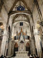 A grand interior of a cathedral showcasing intricate architecture, tall columns, and a prominent altar with an organ in the background.