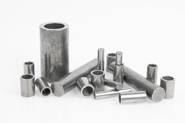Mechanical engineering and metalworking. Metal parts rollers and bushings on white background.