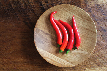 Red hot chili peppers on old wooden table surface texture background