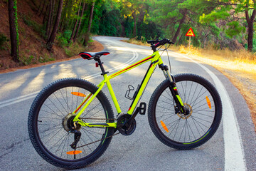 Fototapeta premium Generated imageA bright yellow mountain bike on a winding road in a picturesque forest in a mountainous area. Perfect for travel, active lifestyle and outdoor adventures.