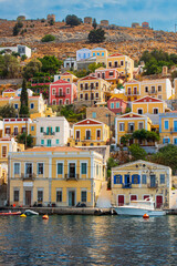 Scenic view of Symi island, Greece, with its traditional colorful houses and impressive monastery on the hillside. Calm sea and authentic architecture, an atmosphere of Mediterranean comfort.