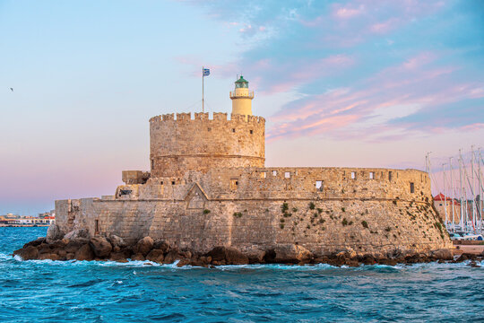 Medieval fortress of Saint Nicholas on the island of Rhodes at sunset. Picturesque landscape with blue sea, yachts and bright sky. Mediterranean atmosphere.