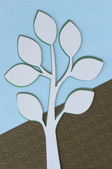 white paper simplified tree form machine-cut on blue paper with dot pattern and brown paper with damask motif