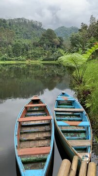 View of Kumpe Lake in Banyumas, Central Java, Indonesia, captured on January 25, 2025. A traditional wooden boat floats on calm waters, surrounded by lush greenery, showcasing Indonesia's serene lands