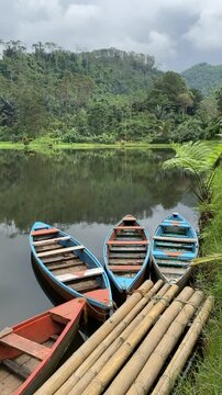 View of Kumpe Lake in Banyumas, Central Java, Indonesia, captured on January 25, 2025. A traditional wooden boat floats on calm waters, surrounded by lush greenery, showcasing Indonesia's serene lands