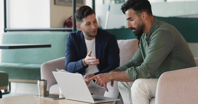 Two young Arab colleagues collaborate in office, reviewing legal documents, using laptop, working on presentation, edit agreement terms, drafting contract, lead formal discussion. Brainstorm, teamwork