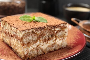Delicious tiramisu with mint on black wooden board, closeup