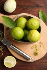 Lime zest, zester, leaves and fresh fruits on wooden table, flat lay
