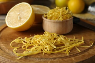 Lemon zest, knife and fresh fruits on wooden table, closeup