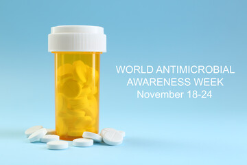 World antimicrobial awareness week. Bottle and scattered pills on light blue background