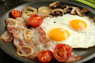 Tasty fried eggs, bacon and mushrooms on frying pan, closeup