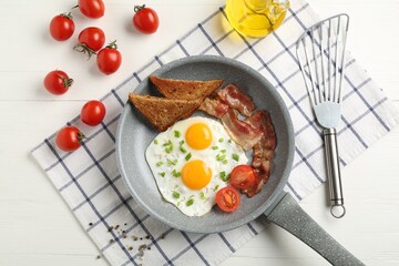Tasty fried eggs with bacon and toasts served on white wooden table, flat lay