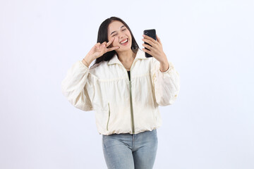 Cheerful Adult Asian Woman Taking a Selfie, Posing Playfully in Casual Outfit
