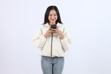 Fototapeta premium Smiling Adult Asian Woman Using Smartphone in Casual Outfit write messages online