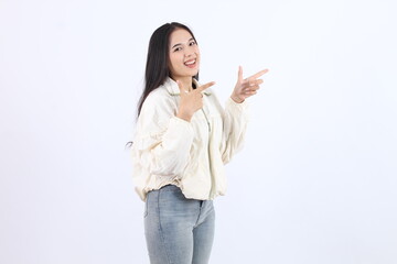 Beautiful woman wearing a white jacket and jeans. She is smiling and pointing to the right.