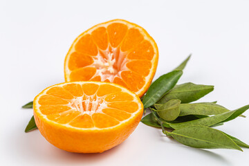 Slice of juicy mandarin with green branch on a white background.
