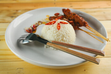 Delicious plate featuring rice and skewers with a colorful garnish served on a wooden table