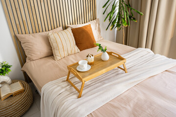 Cozy bedroom setup with breakfast tray and decorative plants in natural light