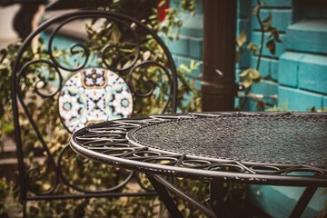 An empty table on the terrace of a cafe, a wrought iron furniture, a cozy atmospheric photo on an overcast day.