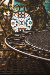 An empty table on the terrace of a cafe, a wrought iron furniture, a cozy atmospheric photo on an overcast day, vertical photo.