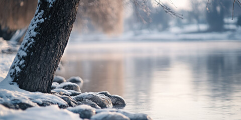 Fototapeta premium A blurred photograph of an icy lake in winter, with snow-covered rocks and trees on the shore. 