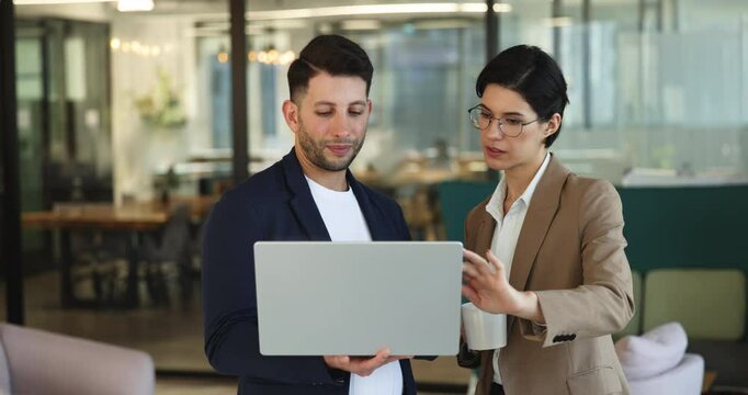Two multiethnic employees, coworkers using laptop met in co-working space, lead conversation, review new corporate software or online project updates, share idea or point during break in office lobby