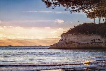 Paysage côtier serein capturé au coucher du soleil, mettant en avant une falaise surplombant...