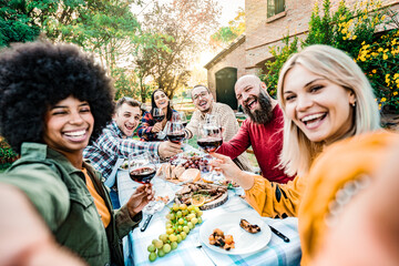 Happy friends having fun at rooftop dinner party - Group of young people taking selfie photo at outdoors dining table - Life style concept with guys and girls eating food and drinking wine together.