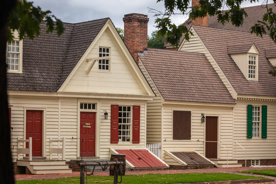 Typical ancient wooden Houses with Sidewalk and green Grass in Foreground in Colonial Williamsburg, Open Air Museum