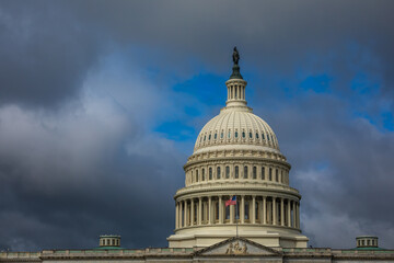 US Capitol Building in Washington, DC - Partial View of the Dome with US Flag; dark Clouds in...