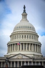Fototapeta premium US Capitol Building in Washington, DC - Partial View of the Dome with US Flag; bright Clouds in Background; Close-up