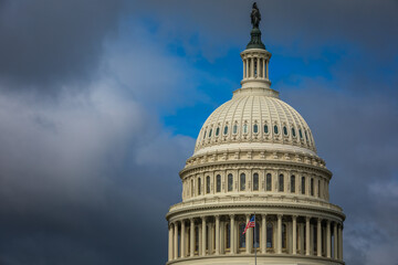 US Capitol Building in Washington, DC - Partial View of the Dome with US Flag; dark Clouds in Background; Close-up with Copy Space