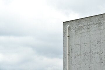 Concrete wall and a single pipe on a cloudy day.