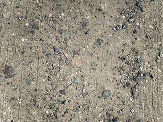 Slag and gravel in the form of small gray stones, seen from above. Old road surface transformed by time and temperature changes into ruins. Dirt road.