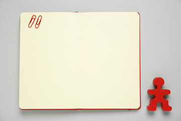 Blank notebook and human figure on light grey background, top view. Space for text