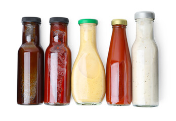 Different delicious sauces in glass bottles isolated on white, top view