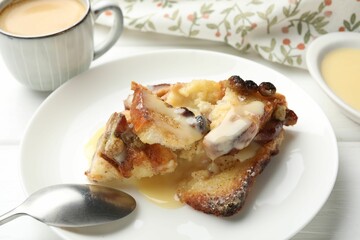 Freshly baked bread pudding and spoon on white wooden table, closeup
