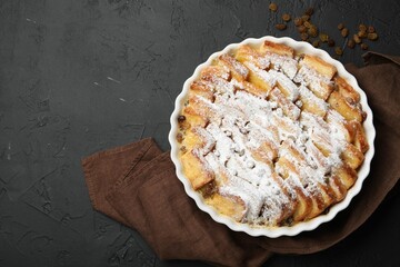 Delicious bread pudding with raisins and powdered sugar on black table, top view. Space for text