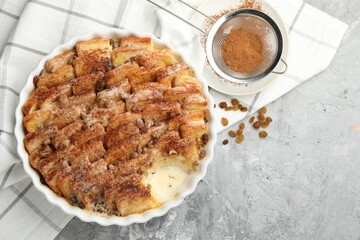 Delicious bread pudding with raisins and cinnamon on grey table, flat lay. Space for text