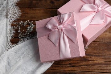 Gift boxes for wedding day and bridal dress on wooden background, flat lay