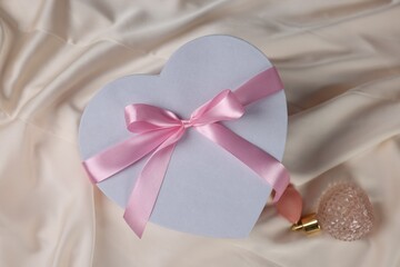 Gift box for wedding day and perfume bottle on beige fabric, flat lay