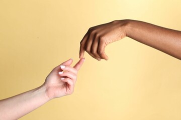 Stop racism. People of different skin colors joining hands on beige background, closeup