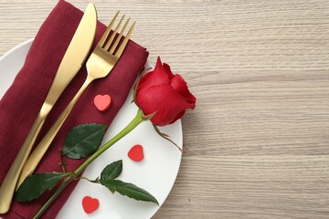 Romantic place setting with red rose on wooden table, top view. Valentine's day celebration