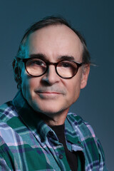Handsome middle aged man wearing glasses & blue checked shirt, headshot
