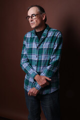 Handsome middle aged man wearing spectacles & blue checked shirt, three quarter length view